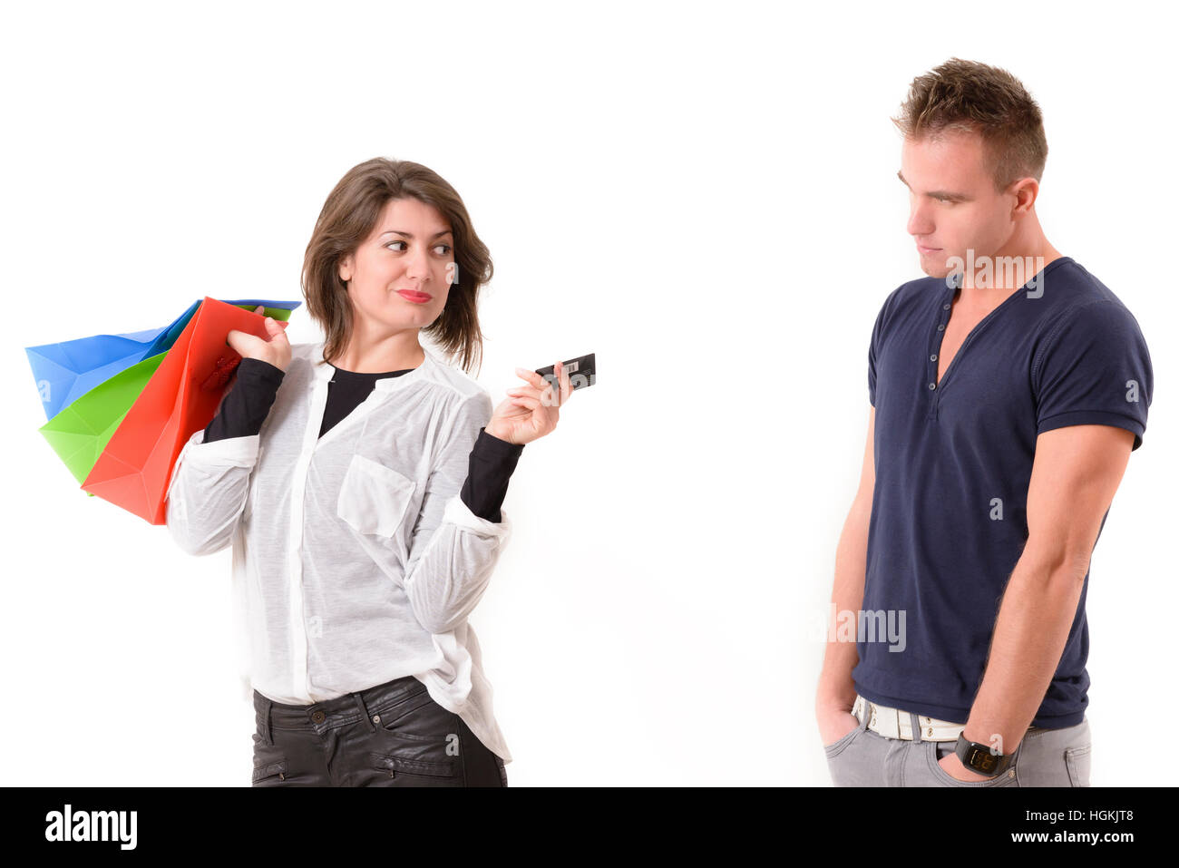Subdolo shopping donna tenendo la carta di credito e borse per lo shopping. Il suo partner è sconvolto. Foto Stock