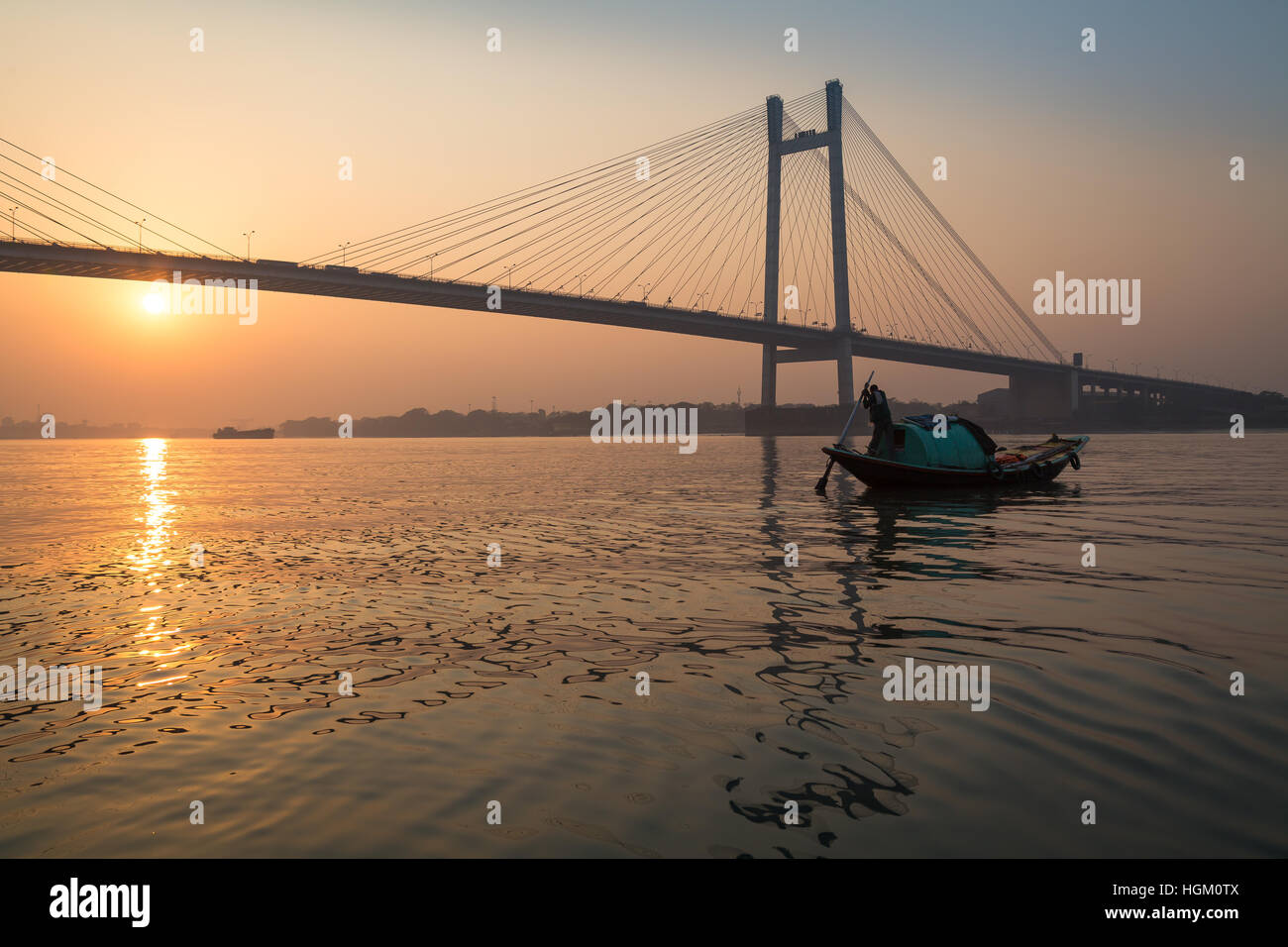 La barca di legno sul Fiume Hooghly al tramonto con Vidyasagar Setu ponte a sfondo. Questo è il più lungo ponte strallato in India. Foto Stock