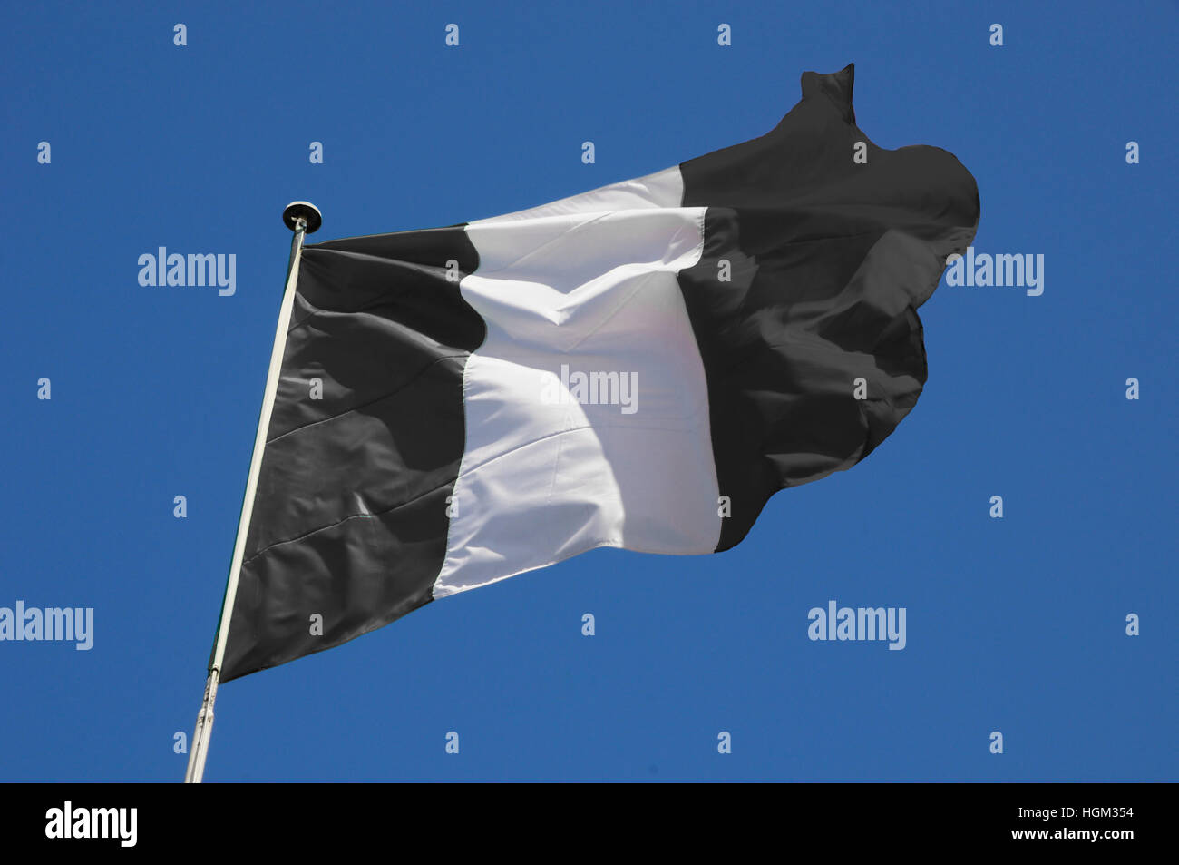 Bianco e nero a strisce bandiera svolazzanti in un vivace brezza contro un luminoso cielo blu. Foto Stock