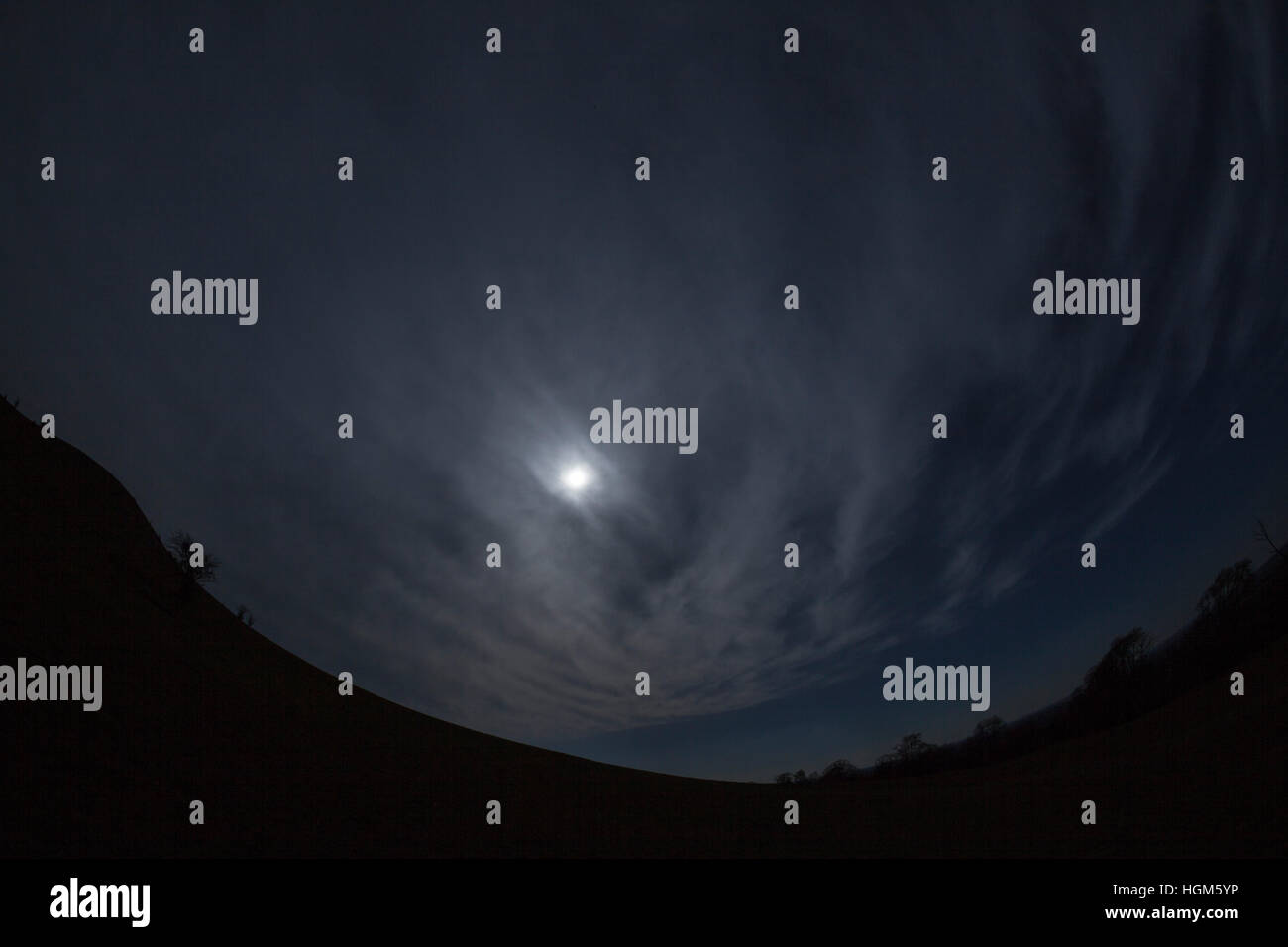 La luna nel cielo di nuvole scure su una collina Foto Stock
