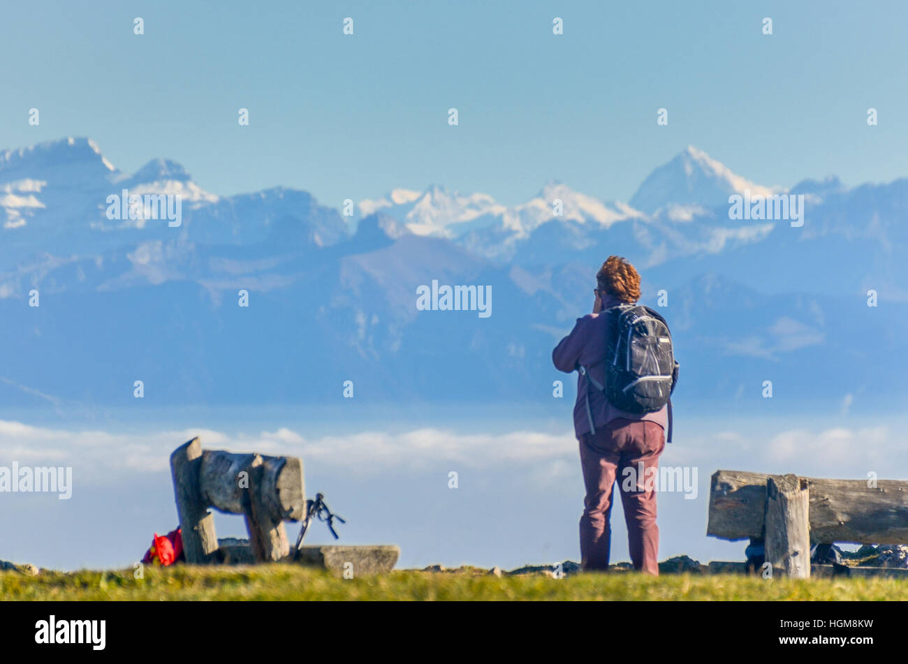 Escursionista di scattare una foto di un panorama delle Alpi Svizzere si vede dal Dent de Vaulion nel Giura Foto Stock