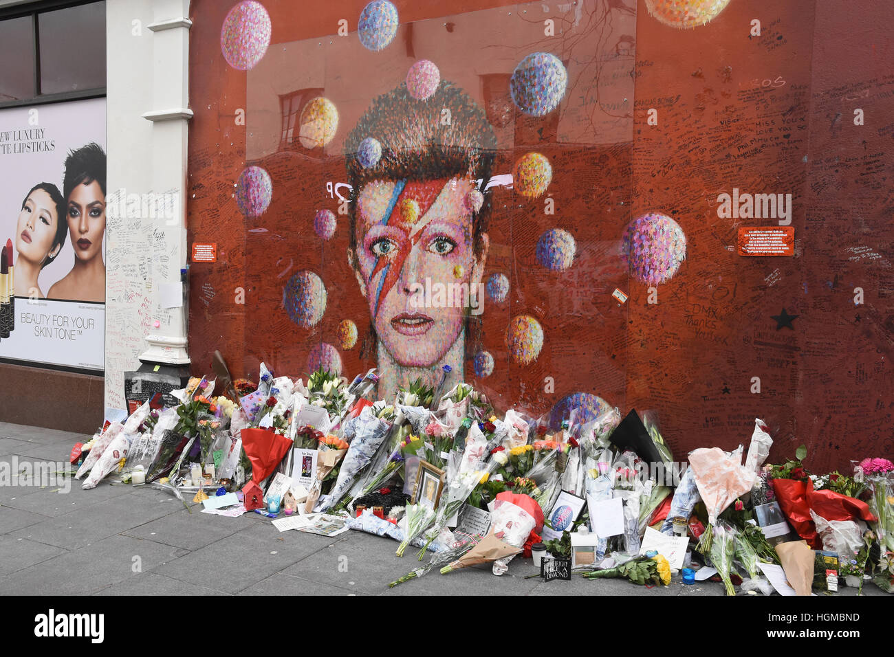 Omaggi floreali di David Bowie a sinistra da appassionati al murale di Brixton nel primo anniversario della sua morte,Brixton,London.UK Foto Stock