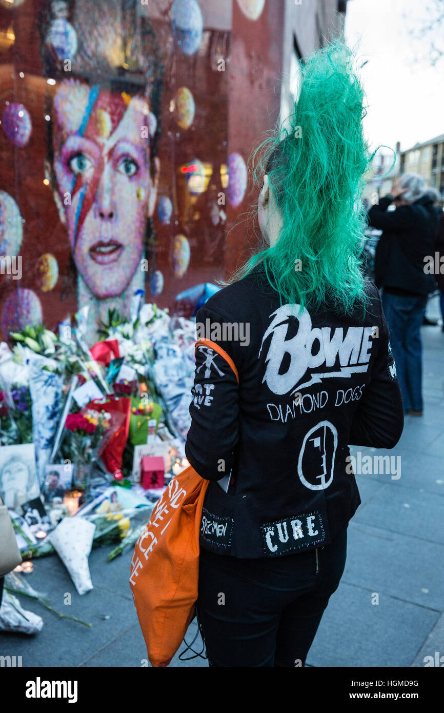 Londra, Regno Unito. Il 10 gennaio, 2017. Una ragazza con una verde mohicano haircut paga il tributo di David Bowie a fronte di un murale di Brixton nel primo anniversario della sua morte. Credito: Mark Kerrison/Alamy Live News Foto Stock