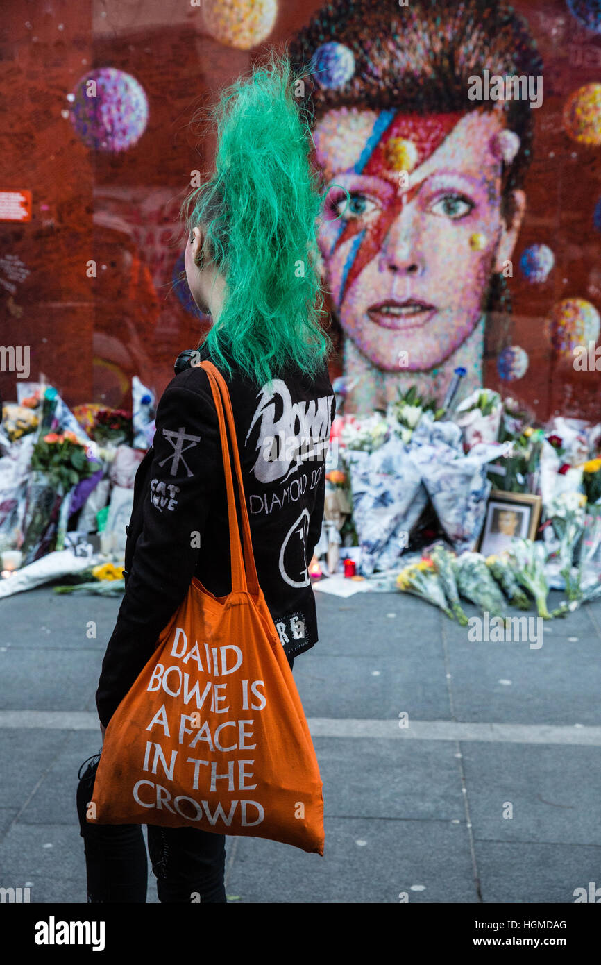 Londra, Regno Unito. Il 10 gennaio, 2017. Una ragazza con una verde mohicano haircut paga il tributo di David Bowie a fronte di un murale di Brixton nel primo anniversario della sua morte. Credito: Mark Kerrison/Alamy Live News Foto Stock