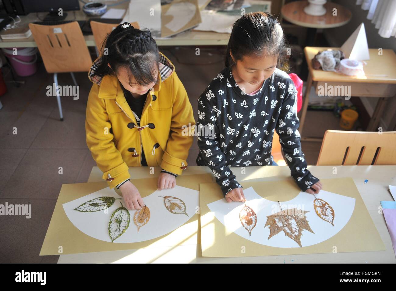 (170111) -- QINGDAO, 11 genn. 2017 (Xinhua) -- Gli studenti mostrano la foglia carving opere "Gallo" di Liu Ping, un insegnante di arte di Qingdao sperimentale scuola primaria, est della Cina di Provincia di Shandong, 11 genn. 2017. Liu ama questo tipo di arte e trascorre il suo tempo libero sulla creazione di varie opere ispirate alla tradizione papercutting. (Xinhua/Wang Haibin) (jqk) Foto Stock