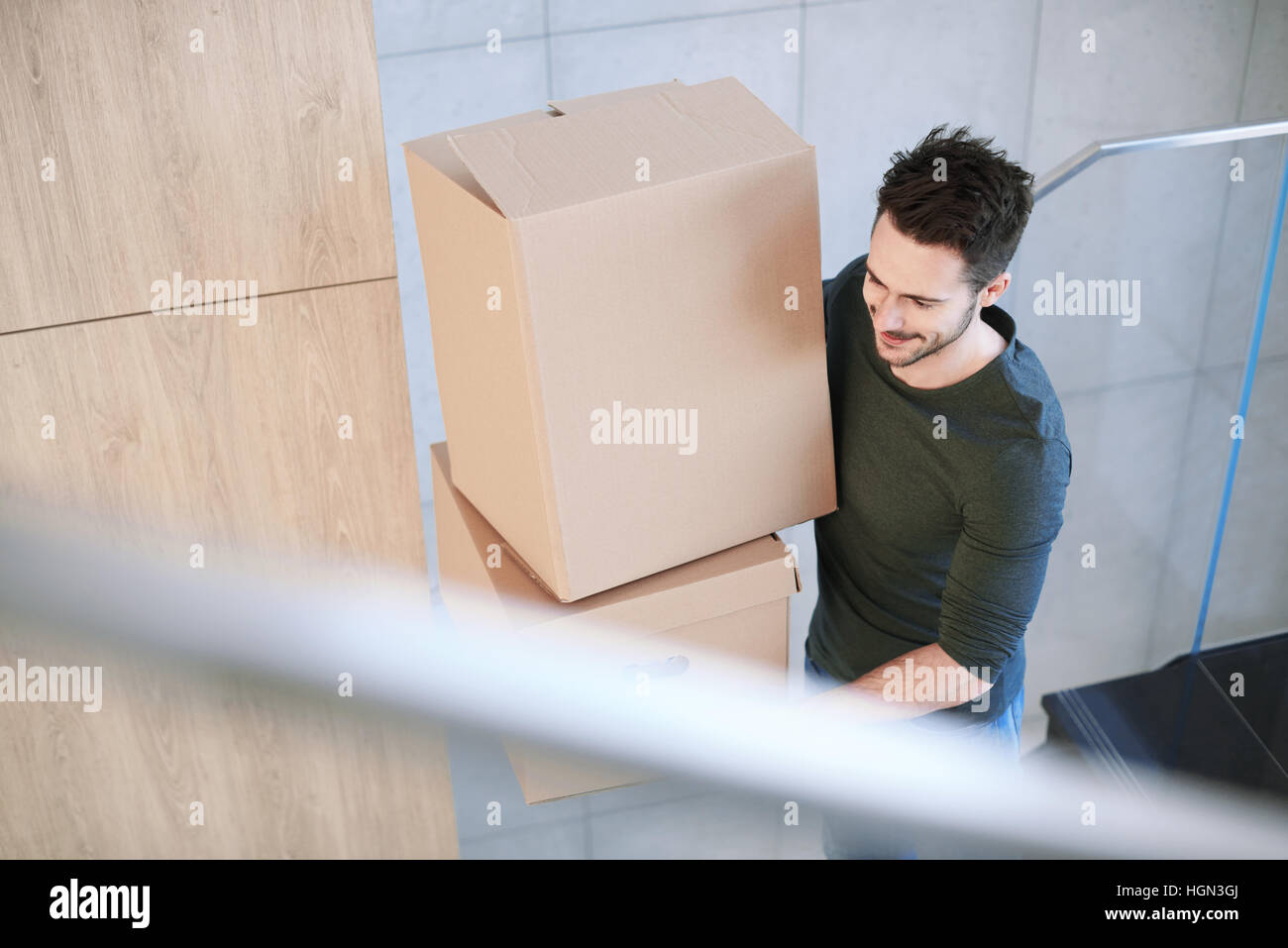 Uomo sorridente e portante scatola di movimentazione in ambienti interni Foto Stock