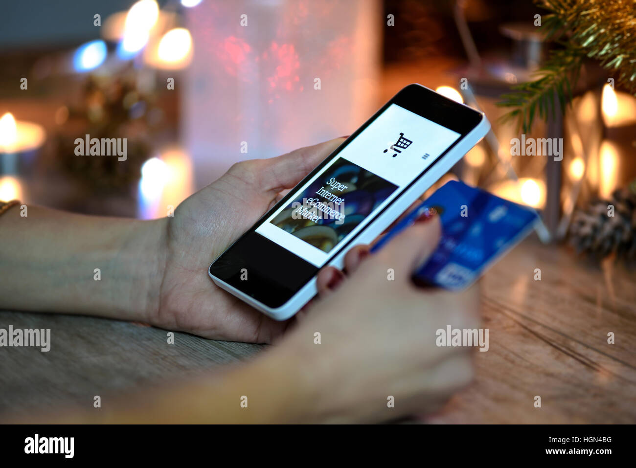 La donna rende lo shopping natalizio tramite smartphone e una carta di credito nel negozio online Foto Stock