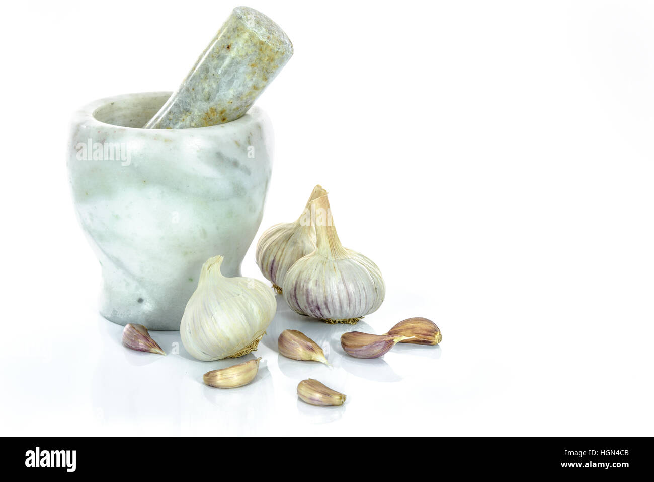 Bulbi di aglio e chiodi di garofano in marmo con mortaio e pestello isolato su uno sfondo bianco. Foto Stock