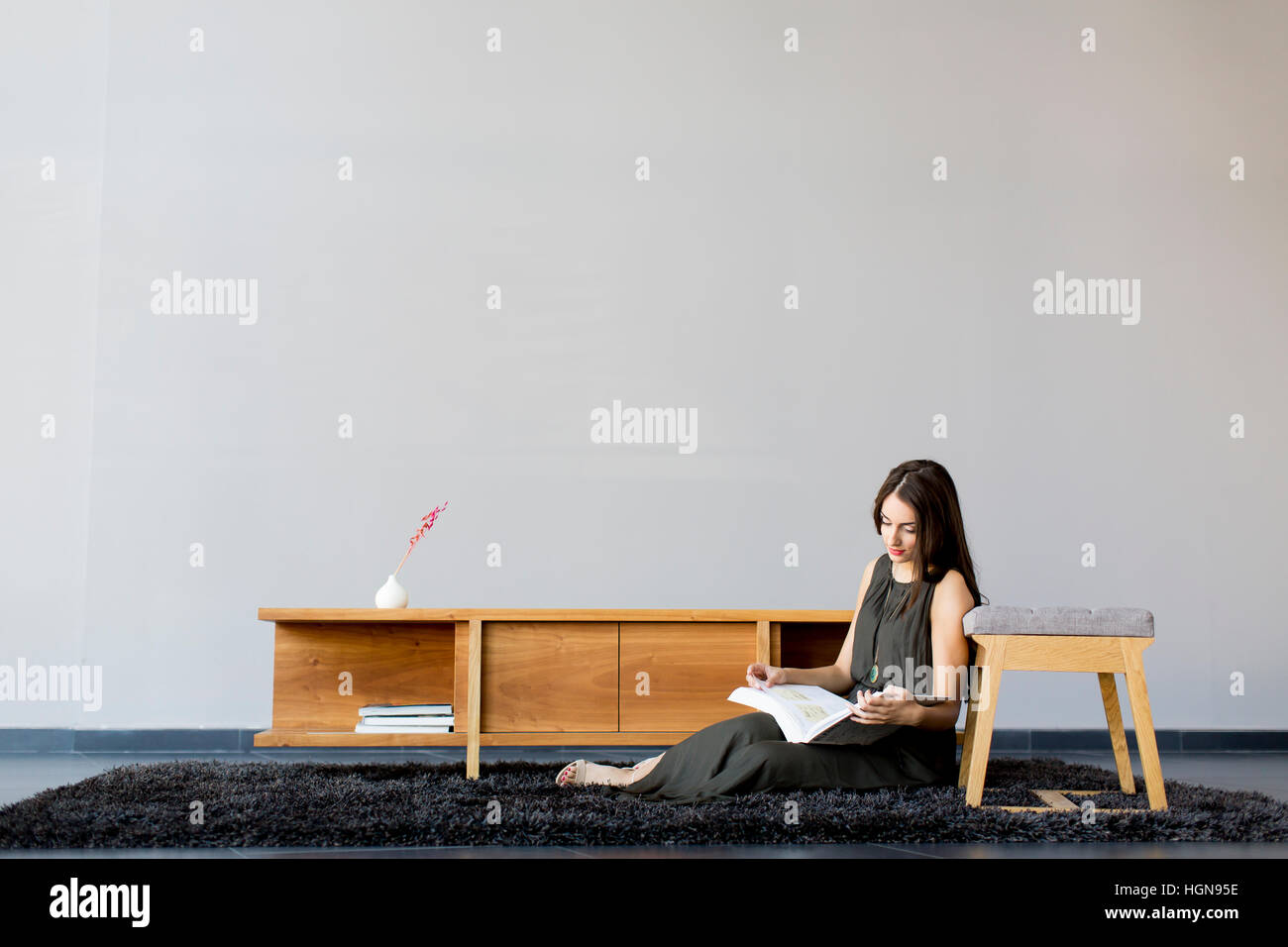 Piuttosto giovane donna leggendo un libro nella moderna sala Foto Stock