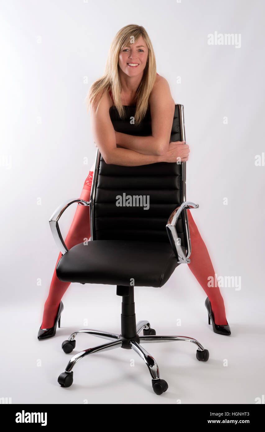 Sexy Blonde donna segretario appoggiato su di una sedia da ufficio Foto Stock