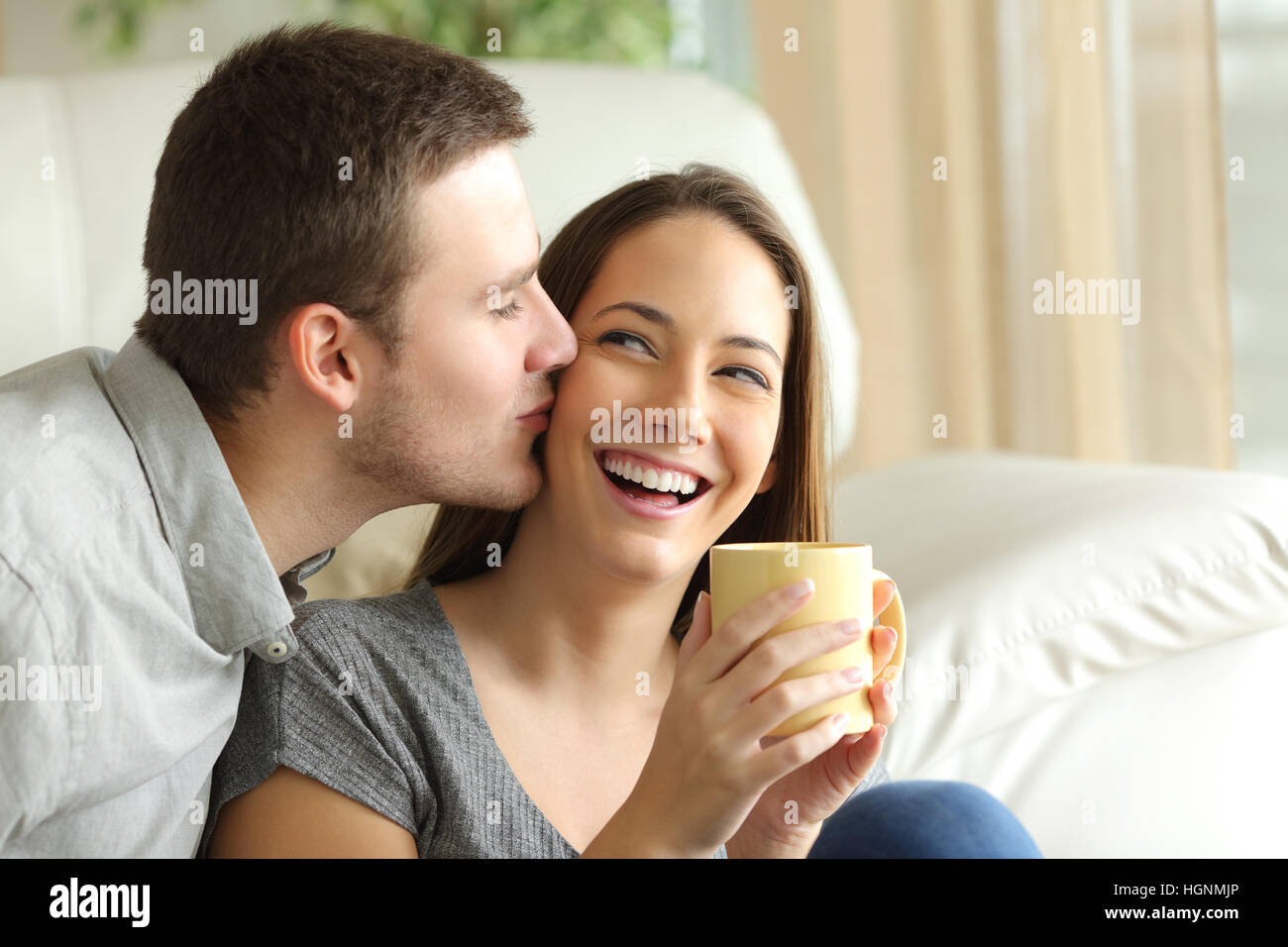 Felice marito baciare sua moglie nel salotto di casa. Coppia felice concetto Foto Stock