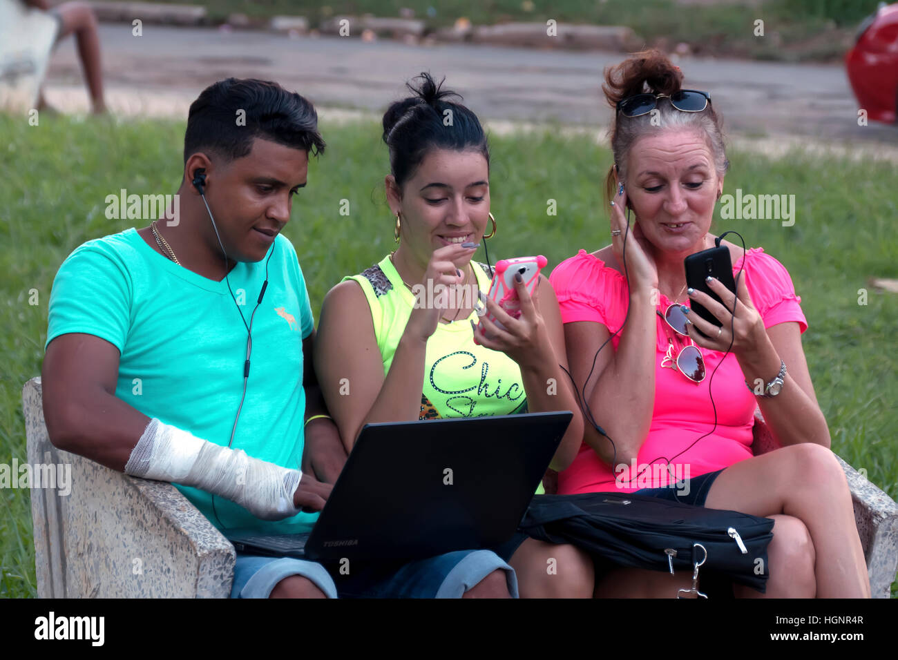 L'Avana, Cuba. Il popolo cubano tramite telefono cellulare, telefono cellulare, lo smartphone e il pc portatile per la connessione internet wi-fi in un parco di Miramar Foto Stock