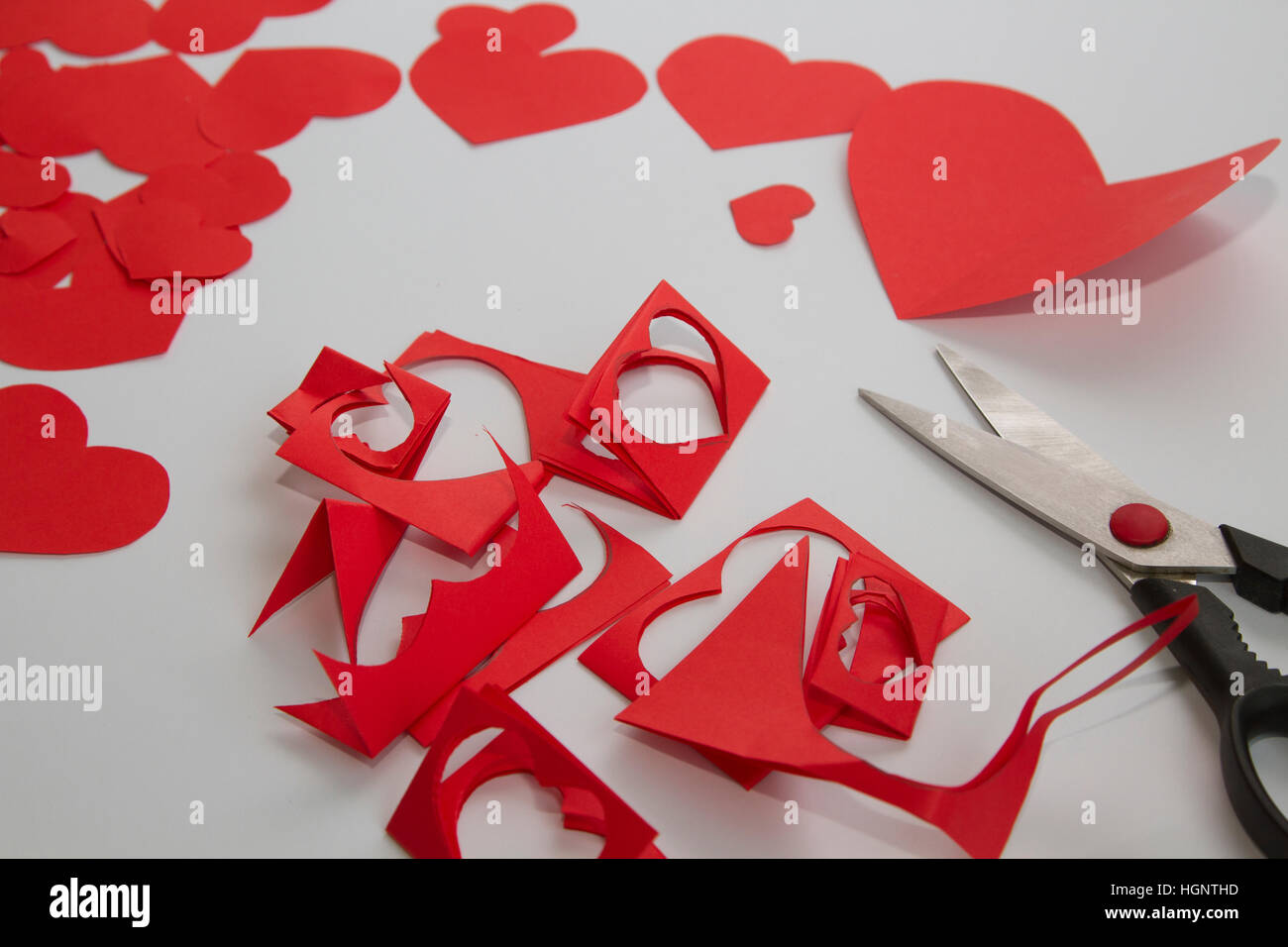 Preparazione dei biglietti di auguri per San Valentino da rosso Cuori di carta e un paio di forbici Foto Stock