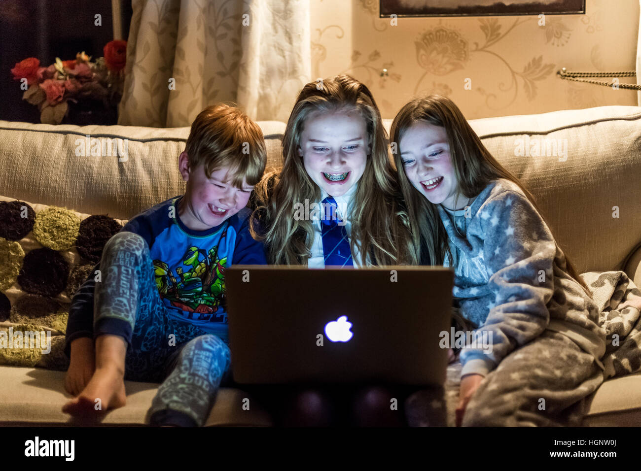 Bambini stavano seduti a casa guardando un computer ridere per uno spettacolo TV Foto Stock