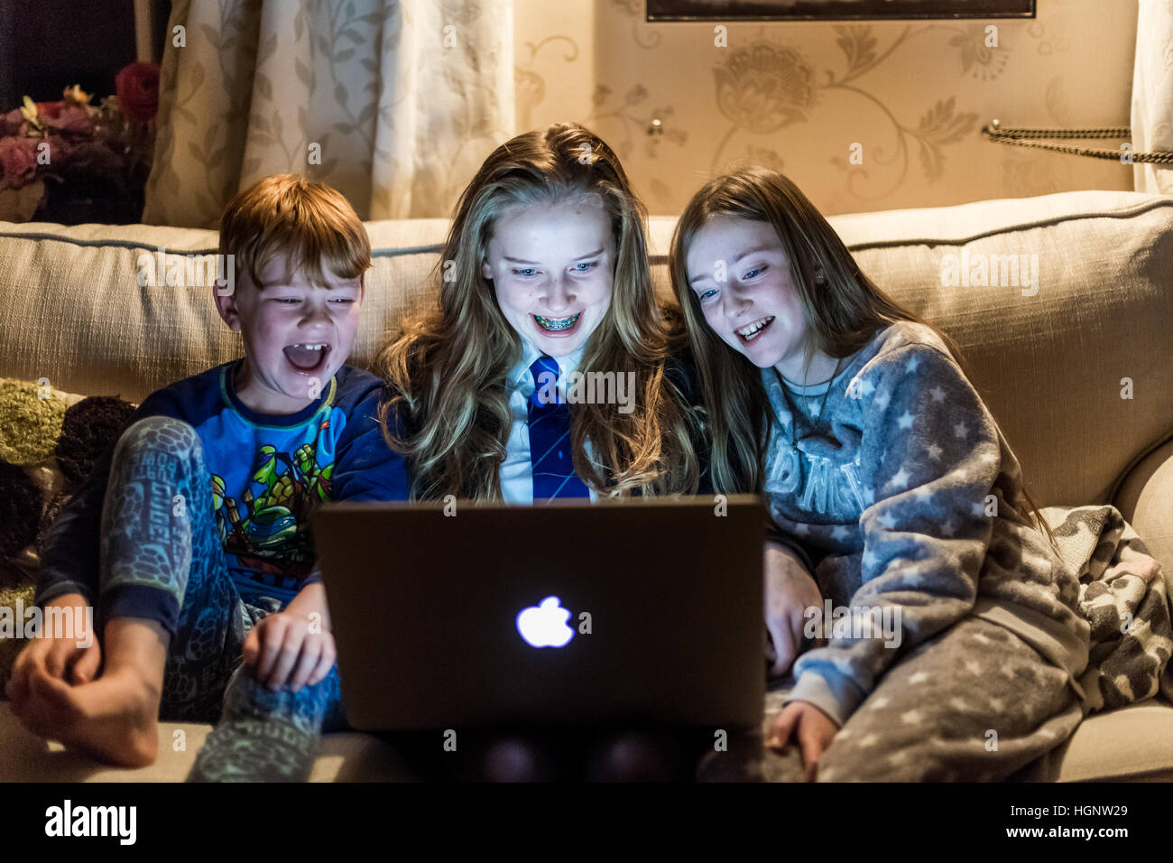 Bambini stavano seduti a casa guardando un computer ridere per uno spettacolo TV Foto Stock