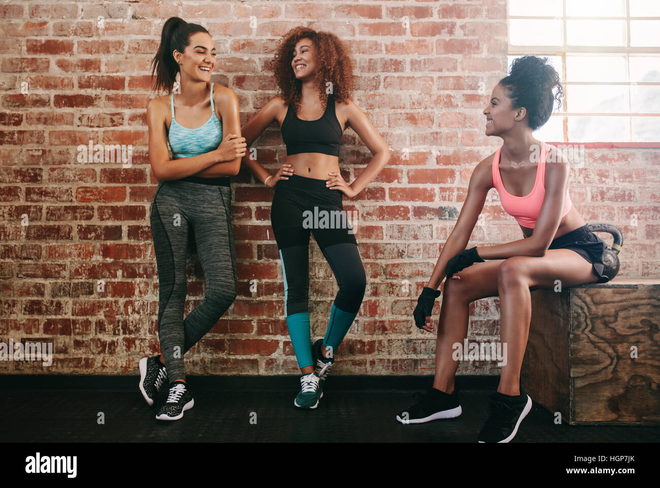 Giovani amici di sesso femminile prendendo il resto dopo allenamento fitness. Felice di giovani donne che parlano in palestra. Foto Stock