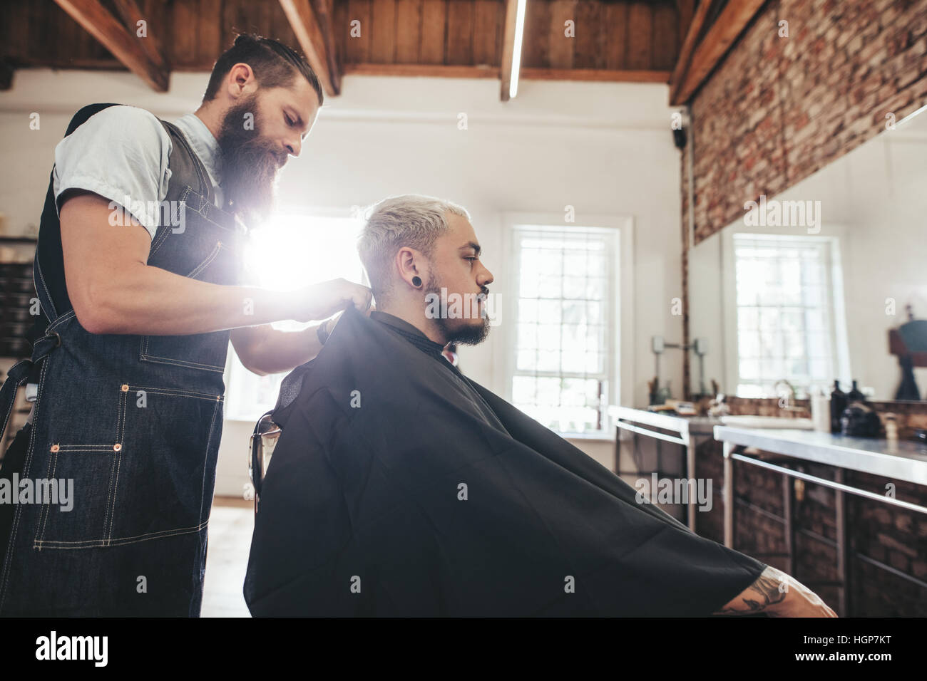 Vista laterale colpo di bel giovane getting haircut in salone. Parrucchiere Servizio client in un barbiere. Foto Stock