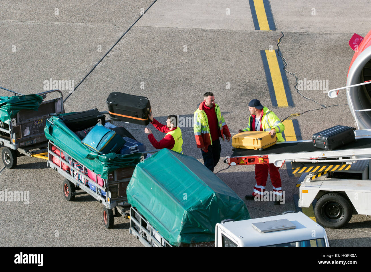 I gestori dei bagagli lo scarico dei bagagli da un aeroplano a Dusseldorf Airport. Foto Stock