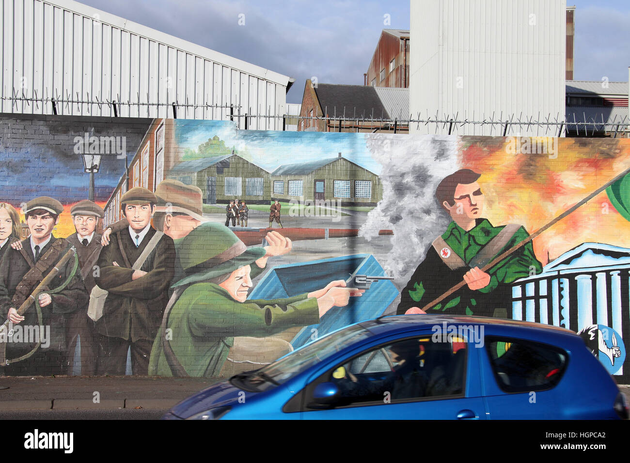 Guida auto giù di Falls Road a Belfast passato la pace internazionale parete Foto Stock