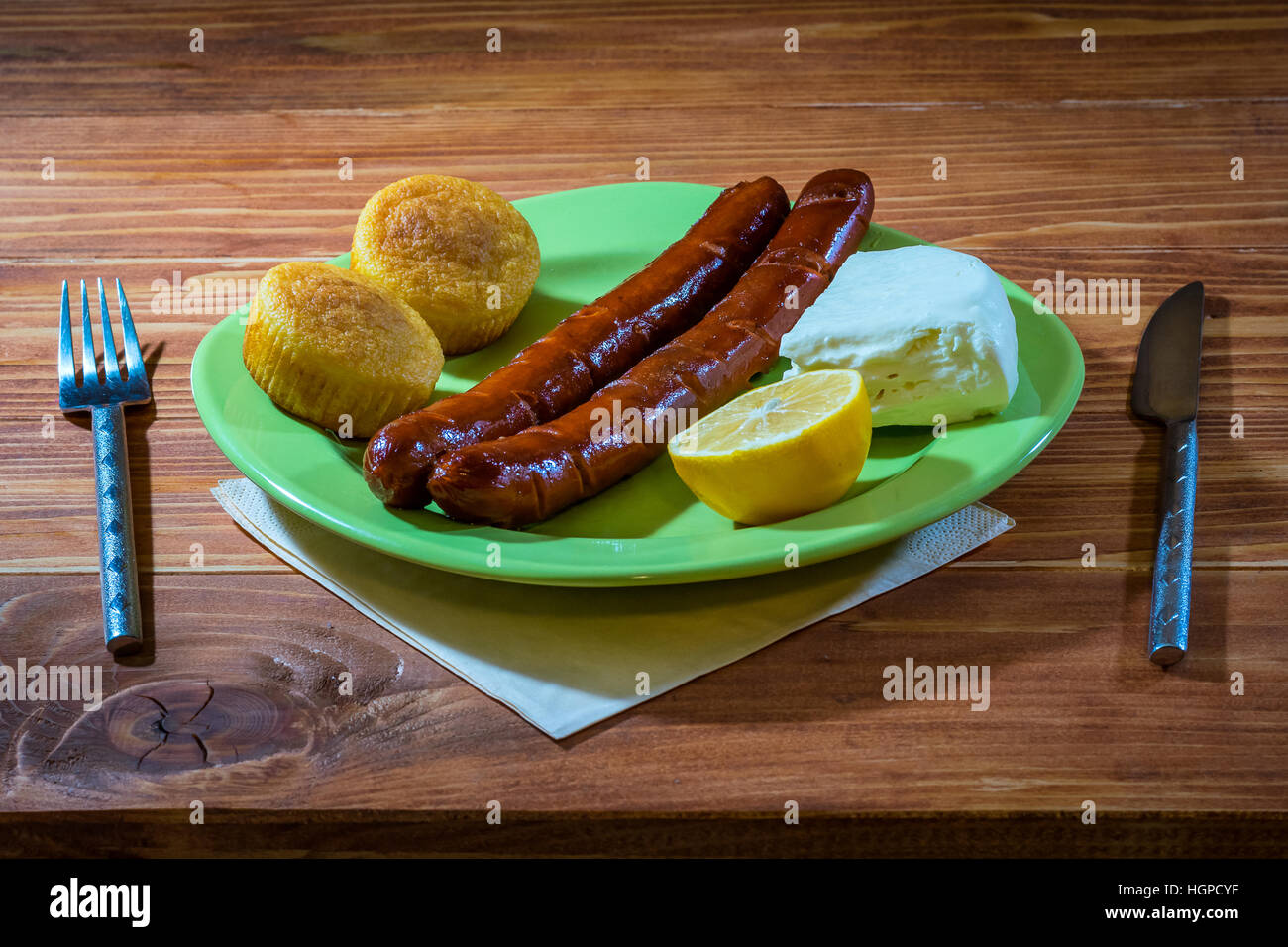 Salsicce alla griglia con grano pane e formaggio bianco servito in una piastra su un tavolo di legno Foto Stock