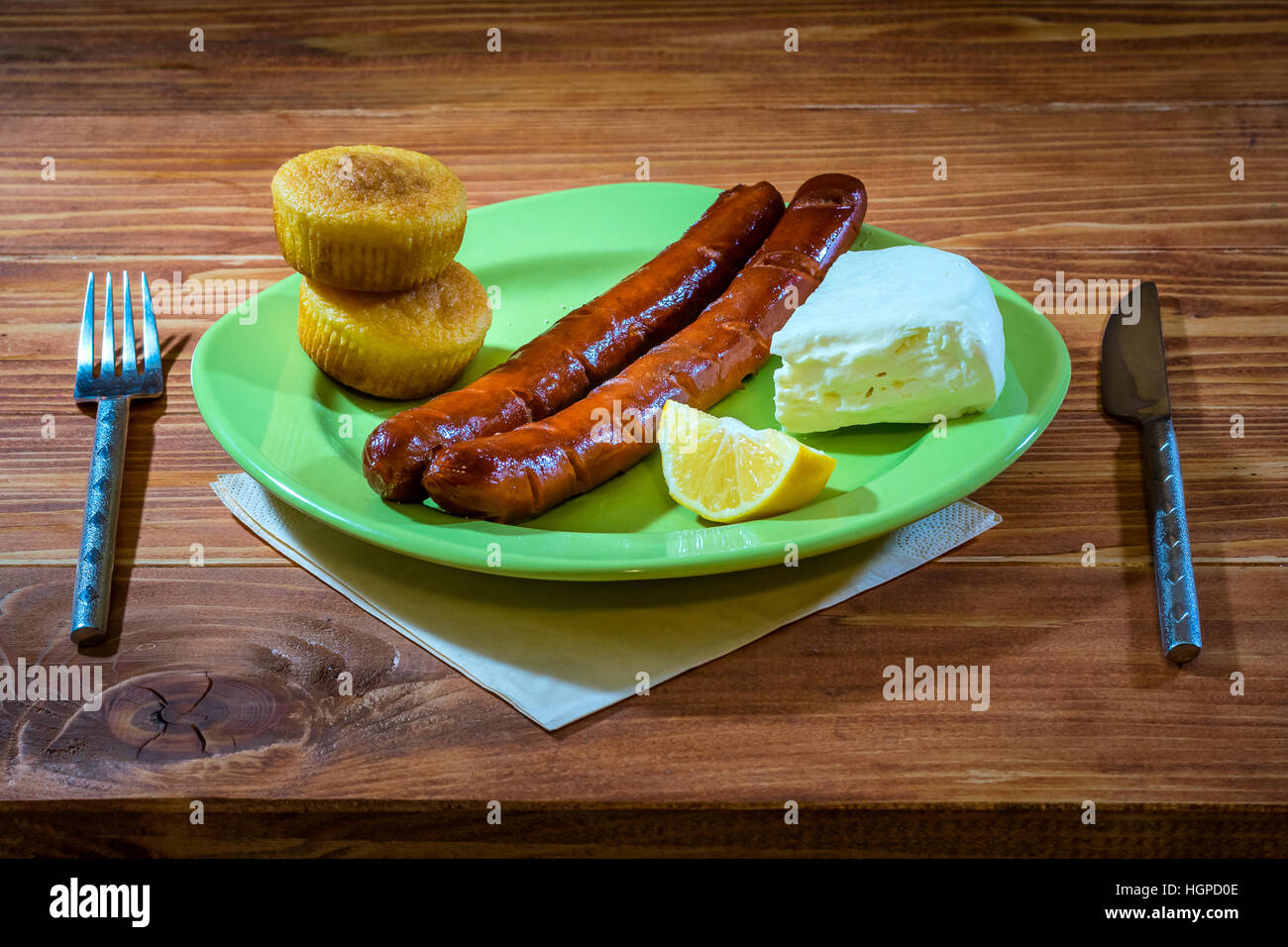 Salsicce alla griglia con grano pane e formaggio bianco servito in una piastra su un tavolo di legno Foto Stock