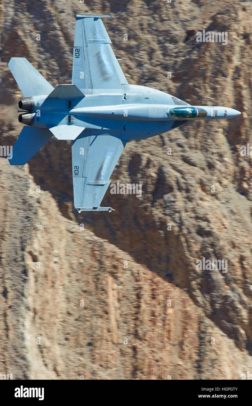 Marina degli Stati Uniti Super Hornet, F-18E, bancario attraverso un canyon del deserto, la formazione di condensa sulle ali di un tira G. Foto Stock