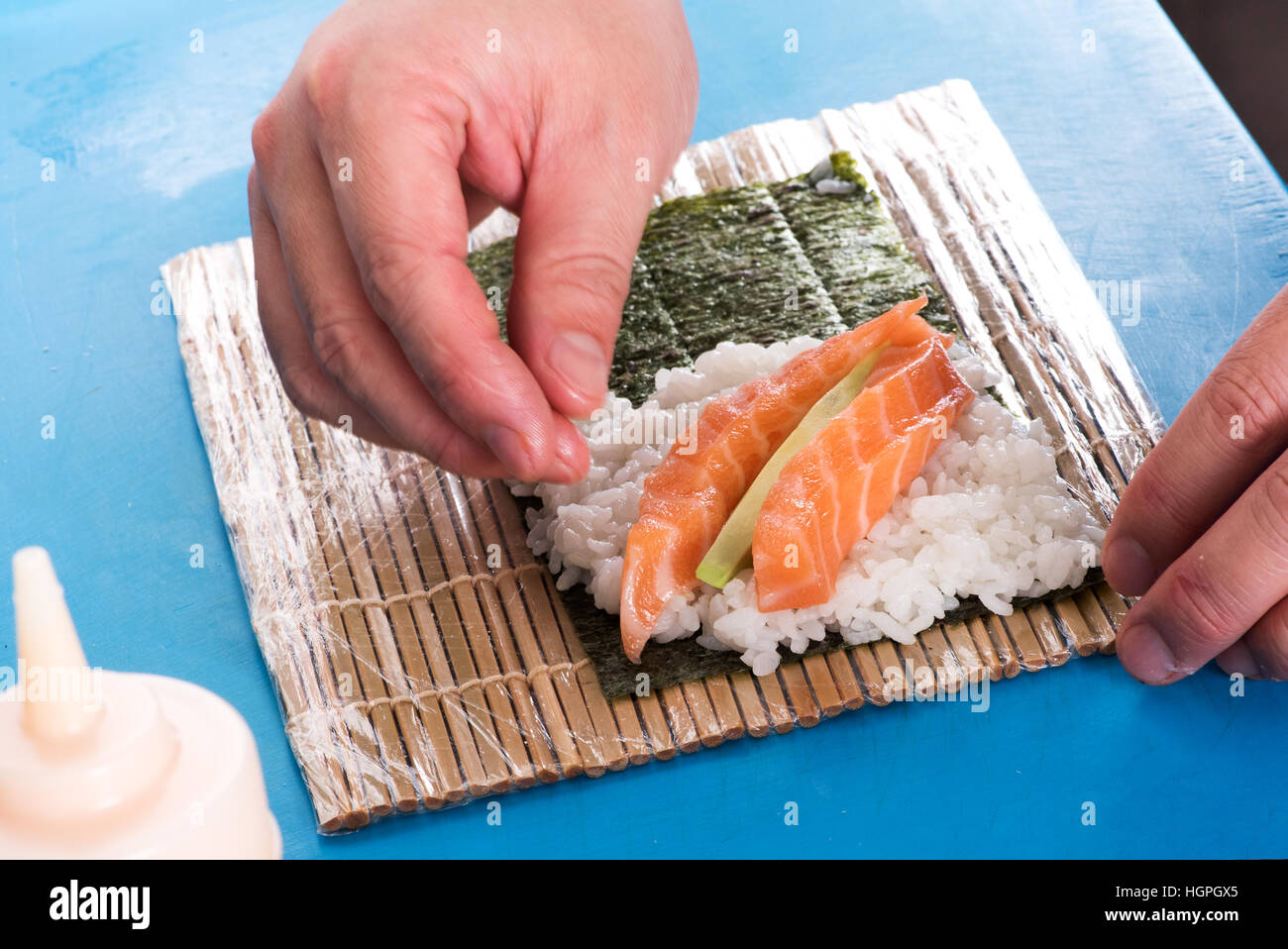 Close up di chef le mani sul tappetino con piatti a base di pesce e per il riso facendo Temaki sushi roll Foto Stock