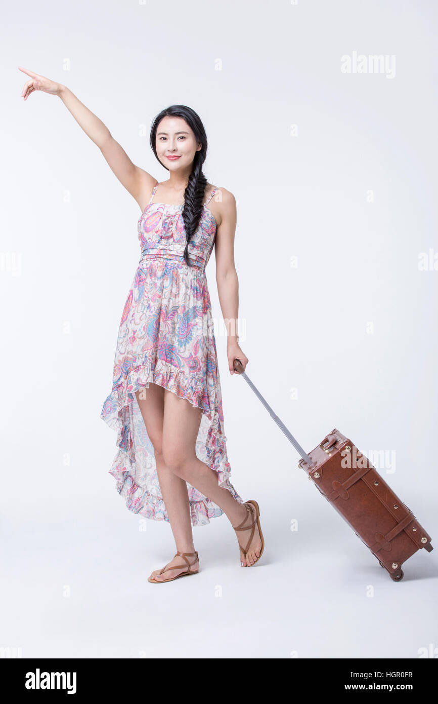 Giovane donna sorridente in abiti estivi tirando un vettore rivolto verso l'alto Foto Stock