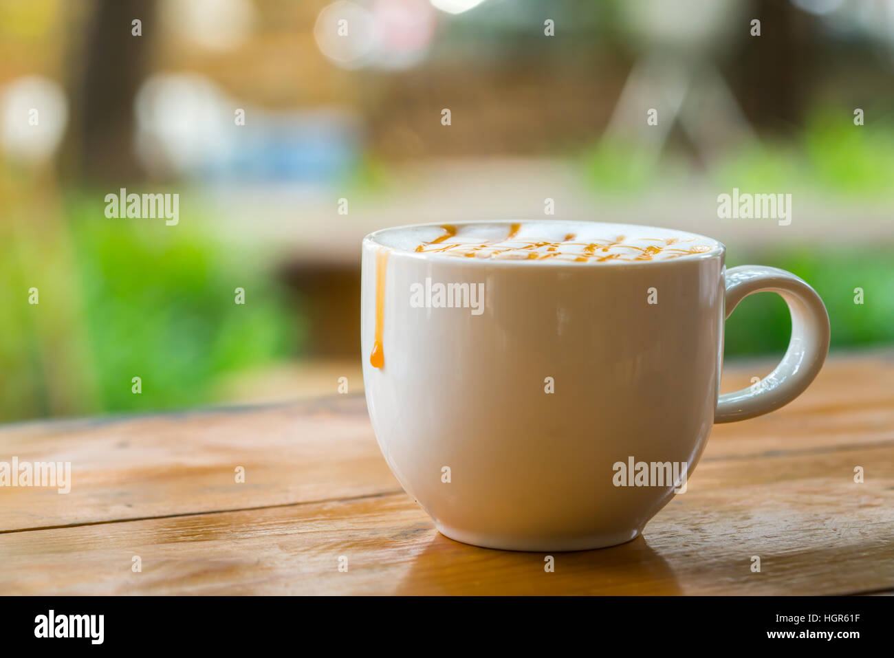A caldo il caffè macchiato con caramello in tazza bianca sulla tavola di legno dalla luce della finestra, copia di sfondo dello spazio Foto Stock