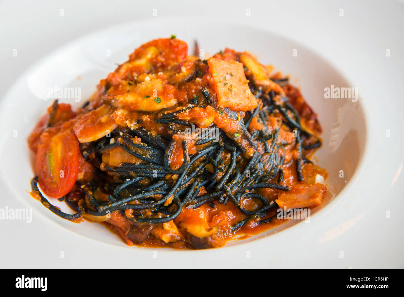Spaghetti al nero di salsa di peperoncino, i frutti di mare con pomodoro crudo nel disco bianco. Foto Stock
