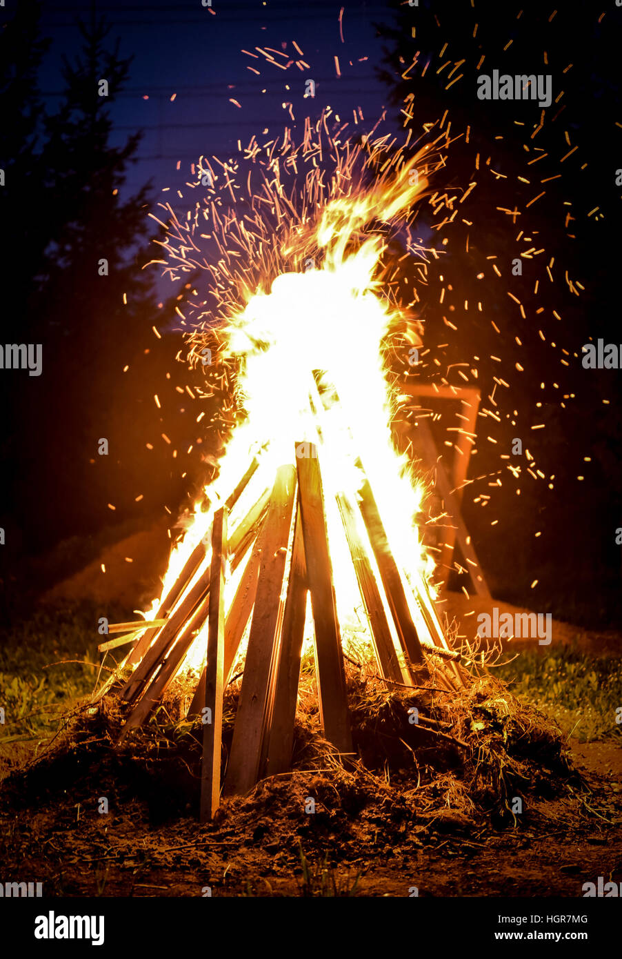 Grandi falò e scintille nella notte. Orange fire sta raggiungendo per il cielo. Forrest e alberi in background Foto Stock