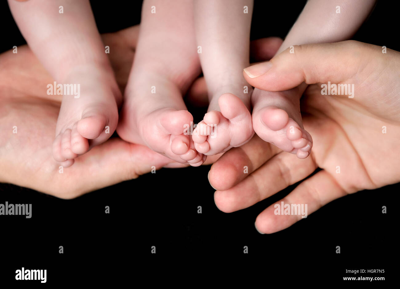 Little Baby gemelli piedi nelle mani dei genitori. Paternità e maternità, famiglia, gemelli, i bambini e il concetto di amore. Foto Stock