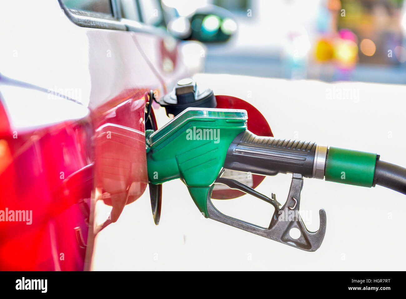 Il rifornimento di un'auto rossa presso la stazione di gas. Un carrello viene riempito con carburante diesel o benzina verde con ugello. Isolato su bianco. Foto Stock