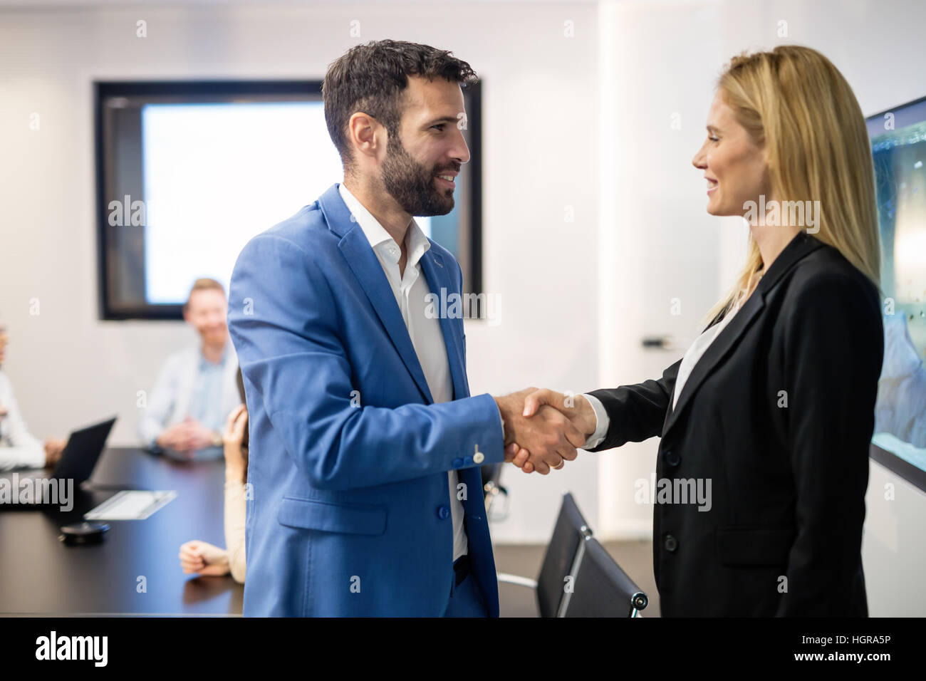 La gente di affari e colleghi agitando mani alla riunione consiglio di amministrazione Foto Stock