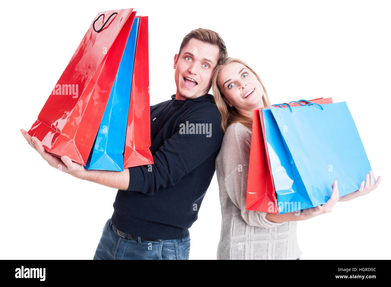 Felice coppia pesante di contenimento delle borse per lo shopping e di agire sorpreso isolato su sfondo bianco Foto Stock