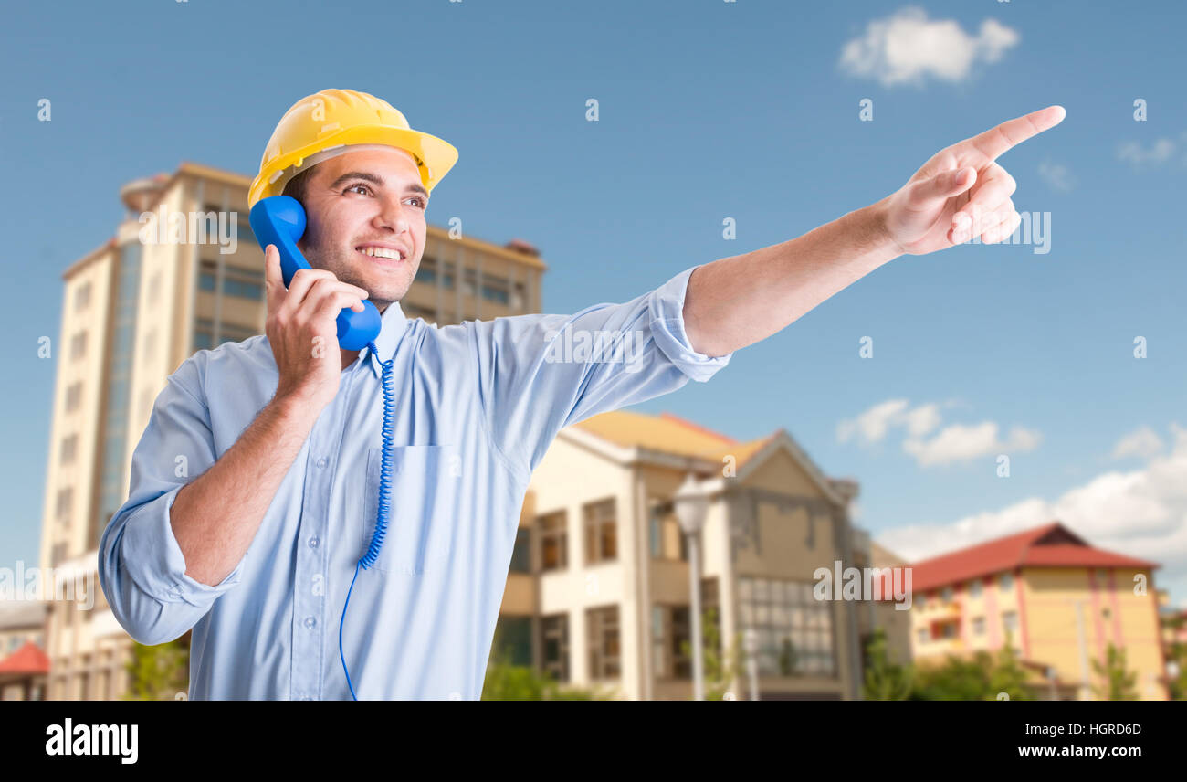 Esterno il concetto di costruzione con bel architetto parlando al telefono e puntare il dito a qualcosa Foto Stock