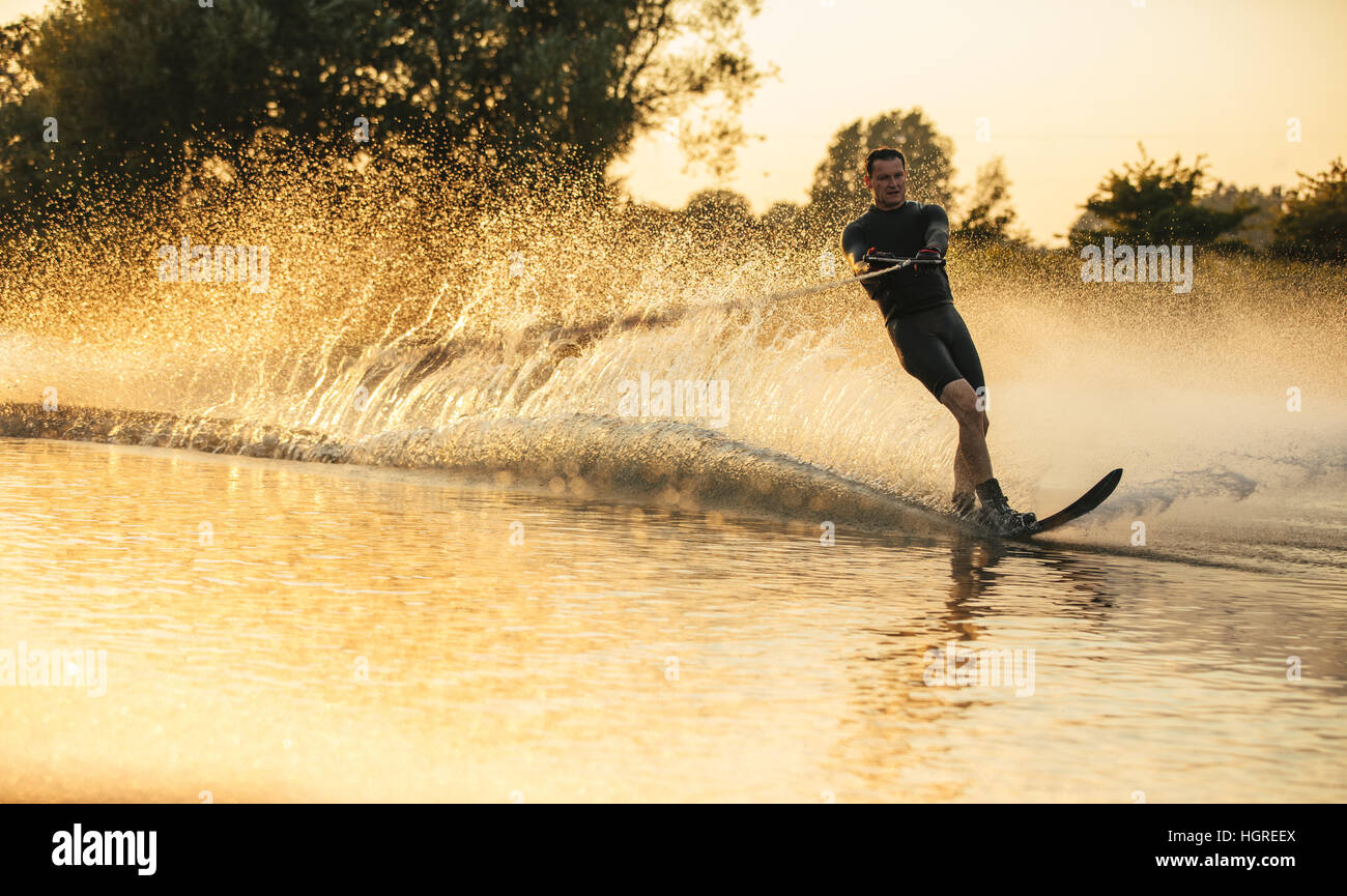 Uomo che cavalca wakeboard in un lago. Acqua sciatore in azione sul lago Foto Stock