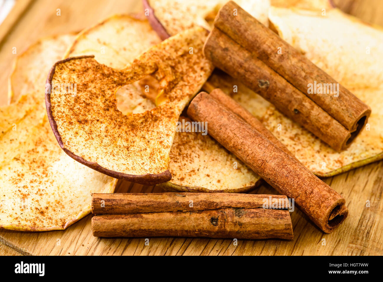 Tutta la cannella e disidratato fette di mela con cannella in polvere sul tagliere di legno. Foto Stock