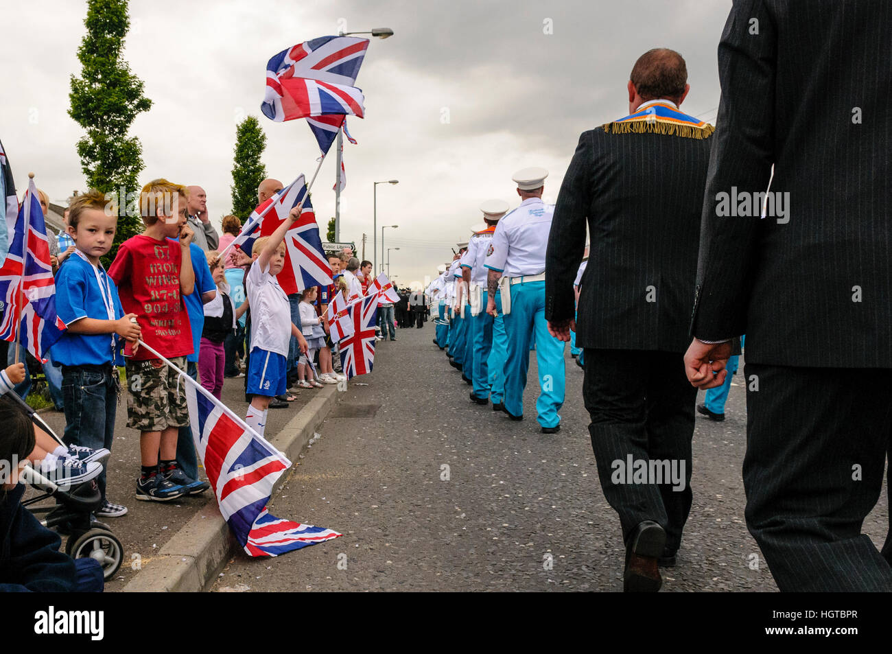 Bambini unione onda di bandiere e di Irlanda del Nord le bandiere durante un ordine arancione parade. Foto Stock