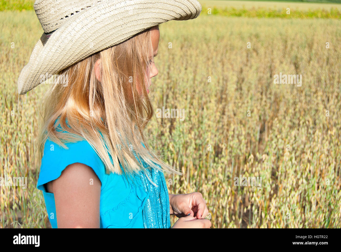 Giovane ragazza bionda che indossa lo stile occidentale e hat nel campo di grano Foto Stock