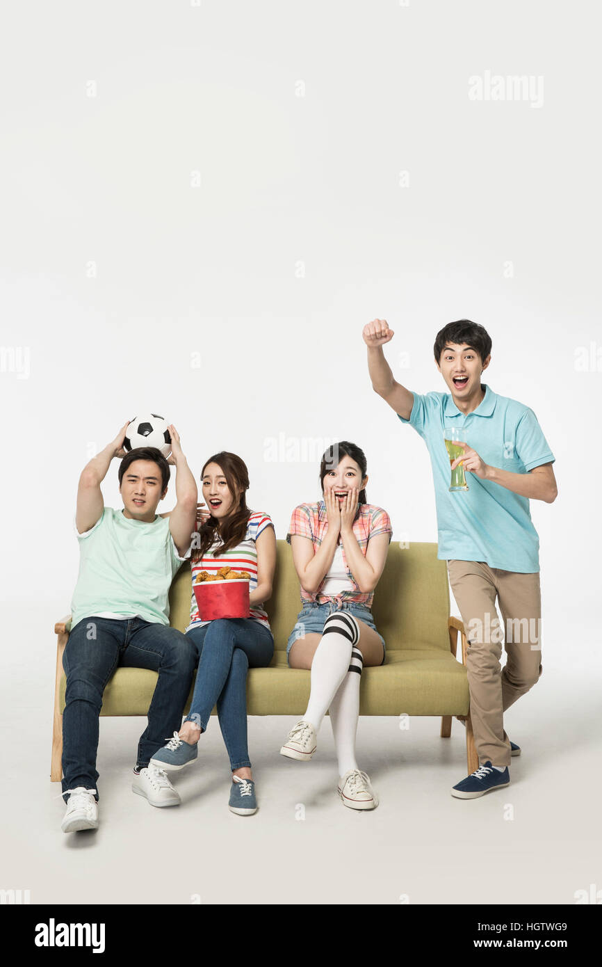 Sorridente giovane popolo coreano il tifo di guardare la TV Foto Stock