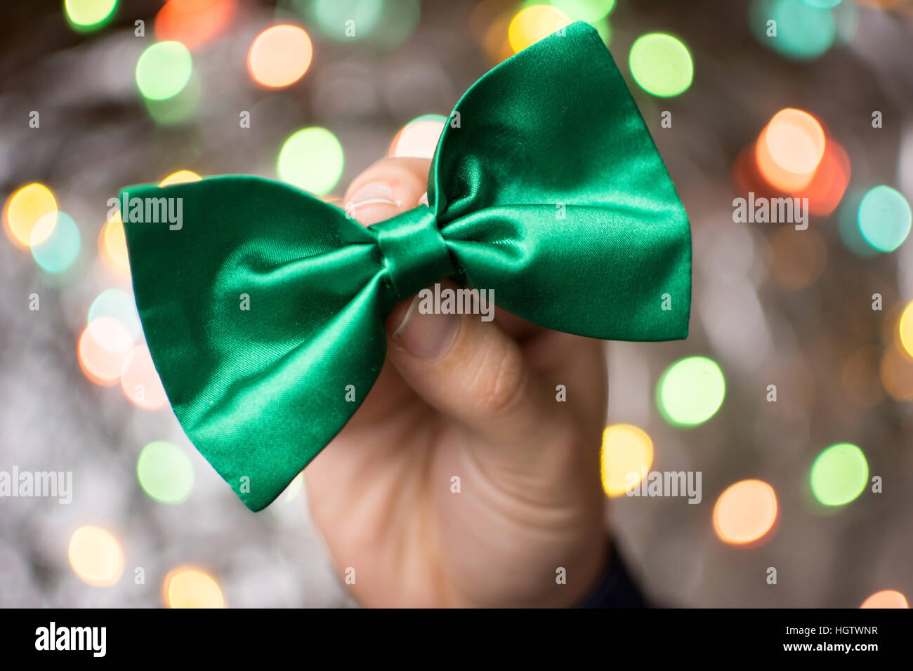 Maschio di mano che tiene un verde il filtro bow tie. Il giorno di San Patrizio preparazione Foto Stock