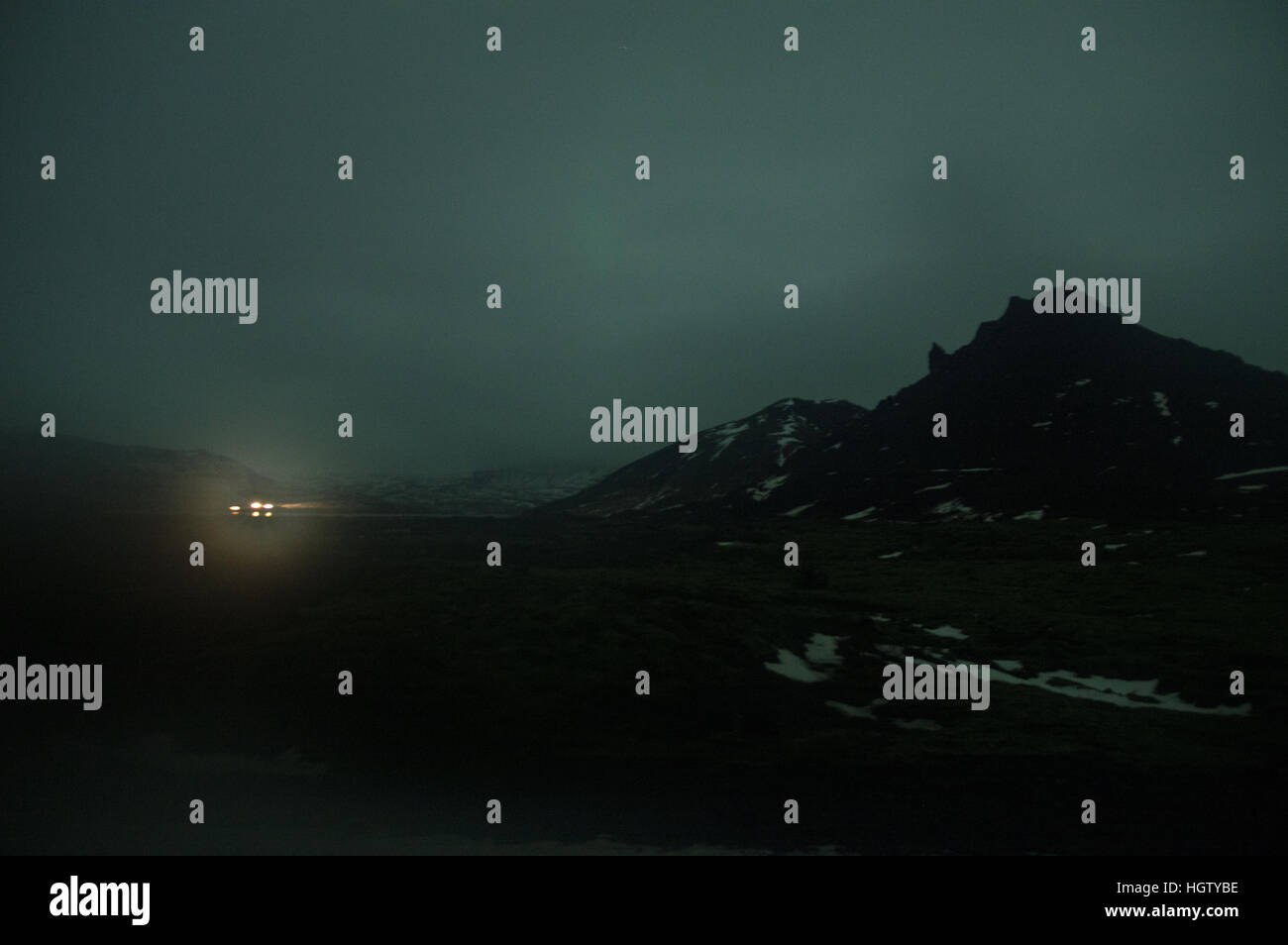 Le luci visto attraverso un inquietante bagliore verde nelle lingue islandese highlands di notte Foto Stock