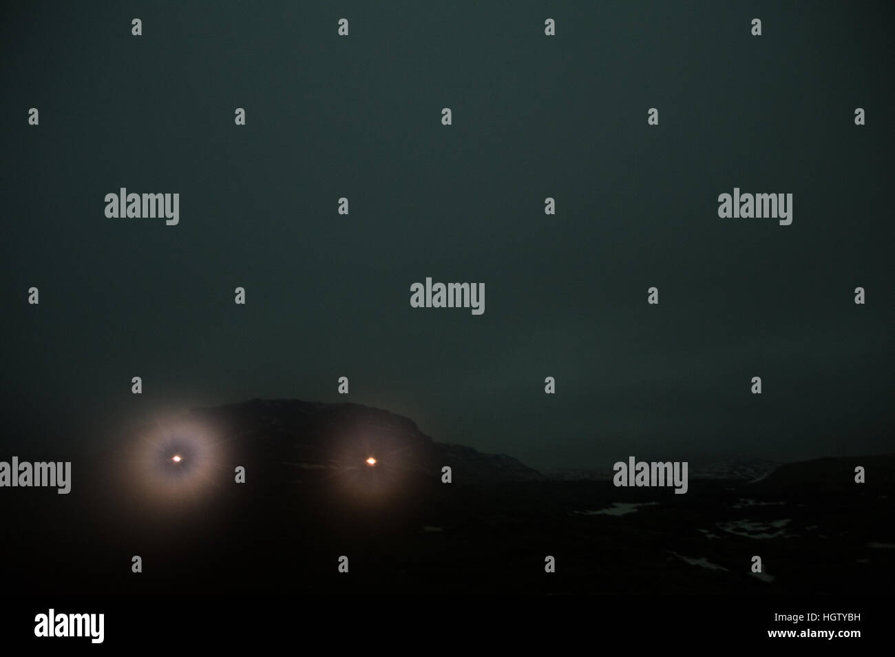Due luci visto attraverso un inquietante bagliore verde nelle lingue islandese highlands di notte Foto Stock