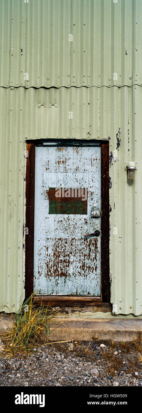 Un cartone ondulato a parete di stagno e sportello in acciaio in una vecchia fabbrica. Foto Stock