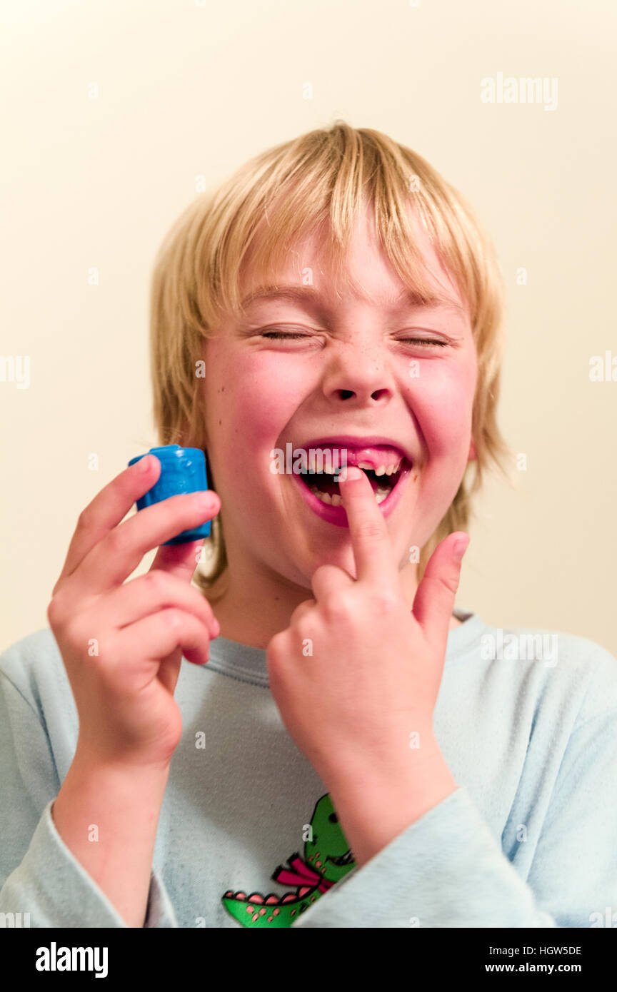 Un ragazzo visualizza lo spazio dove il suo dente è caduto fuori e il suo dente capsula fairy. Foto Stock