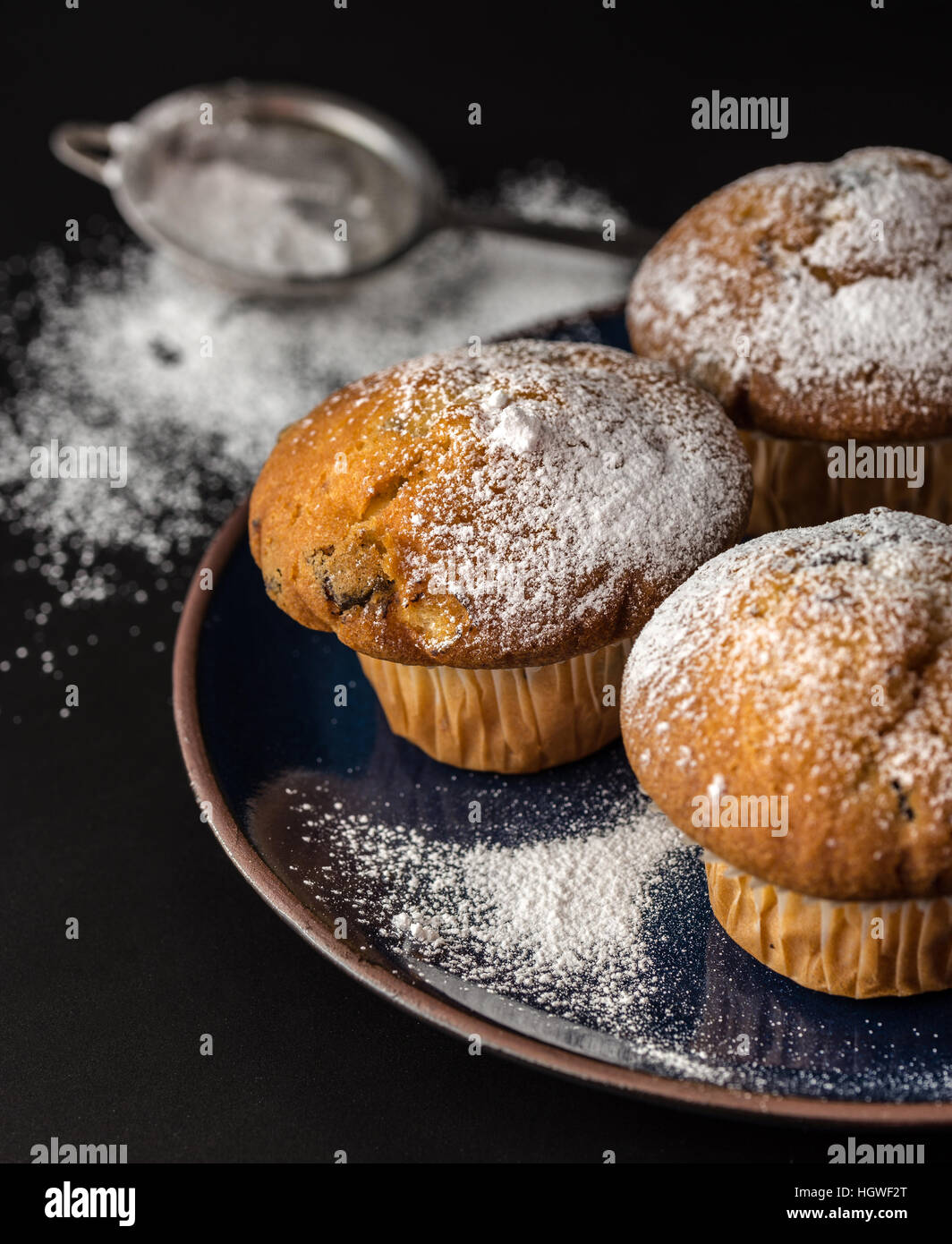 Muffin cosparsa di zucchero in polvere sulla piastra di blu. Foto Stock