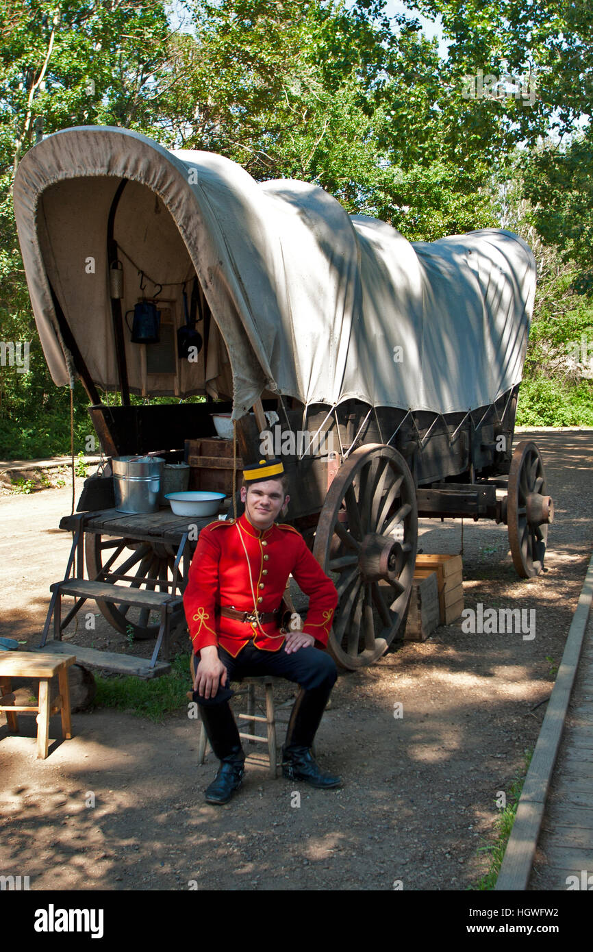 Fort Edmonton, Alberta, Canada, un soldato britannico si siede accanto a un carro coperto, Conestoga carro. Foto Stock