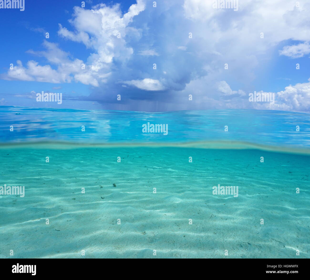 Metà e metà, oceano pacifico seascape, poco profondi fondali sabbiosi subacquei con nuvoloso cielo blu sopra l'acqua, Polinesia Francese Foto Stock
