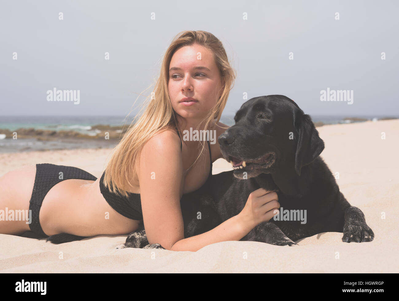 Adolescente bionda con il suo animale domestico labrador presso la spiaggia. Foto Stock